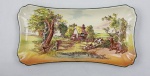 ROYAL DOULTON, Inglaterra. Antiga travessa retangular com nuances em faiaça inglesa tonalidade marfim ricamente policromada com cena campestre e faz parte da série Rustic England. Anos 50.  Medindo: 28 x 15 cm. Craquelê.