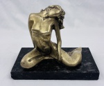 Escultura de bronze Art Déco representando corpo feminino em posse reclinada sobre pedra de mármore negra.
