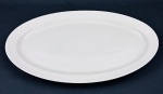 NADIR FIGUEIREDO. Grande e antiga travessa oval  em porcelana branca com borda larga. No verso é exibida uma antiga versão do logotipo do fabricante indicando ser das décadas de 1940 a 1960. Medindo: 4 x 35 x 57 cm. Uma com bicado.