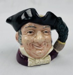 ROYAL DOULTON. Caneca inglesa comumente chamada de TOBY JUG, no qual retrata figuras com trajes históricos e o chapéu servindo como bocal, modelo MINE HOST D6470 caracterizado por sua pintura à mão e design detalhado de personagem. Marcado no verso copyright 1957. OBS Mine Host é um termo arcaico da língua inglesa usado para se referir ao dono de uma estalagem, taverna ou hospedaria, imagem clássica do estalajadeiro alegre, atenciosos e receptivo.  Medindo: 10 x 11 x 7 cm.