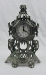 REGULADORA. Antigo relógio português de mesa em metal prateado pesado tipo bronze, à corda, apresentando um estilo barroco/rococó com ornamentos vazados, figuras de querubins e uma coroa no topo. Não funciona. Medindo: 220,00