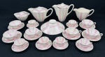 Conjunto em faiança esmaltado com decoração geométrica em tons de rosa, branco e preto, composto por 6 xícaras de chá com seus respectivos pires, 6 xícaras de café com seus respectivos pires, 2 bules, 1 leiteira, 1 açucareiro com tampa e 1 tampa avulsa,. Apresenta fio de cabelo na alça de um dos bules, uma tampa adaptada e uma tampa avulsa. Medidas: bules 15 x 24 cm e 15,5 x 20 cm, açucareiro 7 x 15,5 cm e leiteira 11 x 20 cm.