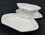 Czechoslovakia. Molheira e espinheira em porcelana esmaltada, de formato oitavado, decorados com delicados ramos florais em grisaille e filetes em prata. Manufatura no verso. Medidas: 7 x 22,5 x 12,5 cm e 3,5 x 11,5 x 22,5 cm.