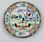 Prato decorativo em porcelana chinesa, com decoração oriental pintada à mão em esmaltação policromada, representando galos, aves e composição floral em paisagem, emoldurada por rica cercadura geométrica com reservas florais, pássaros e delicado filete dourado na borda. Medida: 25 cm de diâmetro.