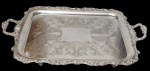 Antiga grande e imponente bandeja em metal espessurado a prata, de formato retangular, com centro gravado em rica decoração de arabescos e folhagens, borda recortada e ornamentada em relevo, com alças vazadas. marcada na baseMedidas: 75 x 47 cm.