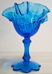 Linda cremeira com pé alto em vidro na cor azul, com bordas ondulas e detalhes florais em relevo. Mede: 16,5x15