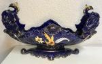 Belíssima floreira em porcelana na cor azul cobalto com pinturas e detalhes de animais antropomórficos na borda ( grifos ) em dourado, Marca : ZAPPI . Mede: 20 x 33 cm.