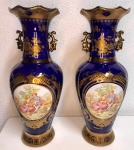 Par de ânforas em porcelana Europeia na cor azul cobalto com dourado, e representação  cena de casal apaixonado. Medem: 33 x 13 cm.