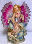 Bela escultura em resina com representação de  anjo e  três golfinhos com pérola. Mede: 33 x 24 cm.