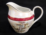 ANTIGA LEITEIRA EM PORCELANA ABECE COM DECORAÇÃO FLORAL . COR VINHO E ORANADA A OURO. MEDINDO 10 X 8.5 X 12.5 CM