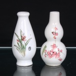 Dois(02) pequenos vasos em porcelana, de formas distintas. O primeiro, de corpo ovoide alongado, assente sobre pequeno pé circular, apresenta colo estreito com bordo espessado e decoração floral composta por folhagens e flores em tons de rosa e verde, realçadas por filetes dourados; na base, marca Made in China em vermelho. O segundo, de corpo constituído por dois bojos globulares sobrepostos e colo cilíndrico alongado, recebe composição floral em tons de rosa e verde, com detalhes dourados. Medidas: Alt.: 10 x Diam.: 5cm.; Alt.: 10 x Diam.: 4,5cm.