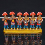 Grupo escultórico popular em terracota, composto por seis figuras de músicos nordestinos, alinhadas sobre base retangular. Personagens representados com trajes típicos regionais, portando instrumentos musicais de sopro e percussão, com vestes em vermelho, azul e amarelo. Medidas: Alt.: x Comp.: x Larg.: