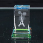 Bloco prismático em cristal incolor, com faces lapidadas e arestas biseladas, apresentando em seu interior gravação tridimensional a laser da Torre Eiffel, circundada por representações de fogos de artifício. Assente sobre base retangular facetada, com efeitos cromáticos nas extremidades. Peça de caráter souvenir alusiva à cidade de Paris. Medidas: Alt.: 5,5 x Comp.: 4 x Larg.: 4cm.