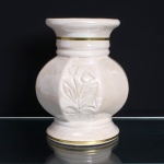 Vaso decorativo em cerâmica esmaltada, século XX. Bojo globular facetado com seis lados, assente sobre pé circular escalonado, com gargalo cilíndrico moldurado e bordo evertido. Superfície revestida por esmalte de tonalidade marfim, apresentando na face principal ornamentação floral em baixo relevo, composta por hastes, folhas e flores estilizadas. Gargalo e base delimitados por filetes dourados. Medidas: Alt.: x Diam.: