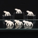 Conjunto de nove(09) miniaturas de elefantes em porcelana esmaltada. Figuras moldadas representadas em posição de marcha, com trombas erguidas e abertura na ponta, orelhas abaixadas e formas corporais definidas em relevo. Revestimento monocromático em esmalte branco. Conjunto composto por exemplares de dois tamanhos. Sem marca de manufatura. Medidas: Alt.: x Comp.: x Larg.: