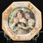 Porcelana Schmidt, Santa Catarina, Brasil (Fundada em 1945). Prato decorativo em porcelana, coleção Victorian Dreams  Pet and Toy Collection, Schmidt, segunda metade do século XX. Formato octogonal, aba decorado com efeito lustreware (iridescente/madrepérola) com padronagem marmorizada em tons de bronze, ocre e dourado, rematada por filetes dourados. Ao centro, reprodução policroma de composição de inspiração vitoriana, representando três meninas acompanhadas de coelho de estimação. No verso, inscrições "VICTORIAN DREAMS  Pet and toy  COLLECTION" e marca da manufatura "SCHMIDT". Medida: Diam.: 26,5 cm.