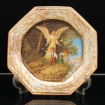 Porcelana Schmidt, Santa Catarina, Brasil (Fundada em 1945). Prato decorativo em porcelana, coleção Victorian Dreams  Pet and Toy Collection, segunda metade do século XX. Formato octogonal, aba decorada com efeito lustreware(iridescente/madrepérola), com padronagem marmorizada em tons de bronze, ocre e dourado, rematada por filetes dourados. Ao centro, reprodução policroma da composição "Schutzenge"l(Anjo da Guarda), representando figura angelical de asas abertas acompanhando duas crianças à margem de um caminho, em paisagem arborizada, com borboletas. No verso, inscrições "VICTORIAN DREAMS  Pet and toy COLLECTION" e marca da manufatura "SCHMIDT". Medida: Diam.: 26,5 cm.