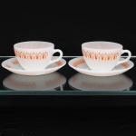 Duas(02) xícaras para café em vidro opalino de tonalidade branco leitoso, dotado de decoração aplicada por estampagem de tonalidade laranja, padrão geométrico conhecido popularmente como "gravatinha", replicado na aba do pires. Fabricado no Brasil pela empresa Brasividro S.A., sob a marca Termo-Rey, durante a década de 1970. Medidas: Xícara: Alt.: x Comp.: x Larg.: ;Pires: Diam.: