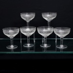 Conjunto de seis(06) taças em meio cristal incolor,bojo em formato de coupe,  dotado de ornamentação executada em gravação, organizada em faixas concêntricas: friso superior de elementos lanceolados sucessivos e, abaixo, composição contínua de volutas, círculos e entrelaçamentos geométricos. Medidas: Alt.: x Diam.: