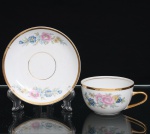 Porcellana Mauá, Mauá - SP(Fundada em 1937 por Fritz Erwin Schmidt / ativa até 1968). Xícara para chá em porcelana, esmaltagem vítrea na cor branca, bojo hemisférico, apoiado sobre pequeno pé anular, com alça lateral arqueada. Ornamentação floral em estampagem policromada composta por ramagens com flores em rosa, azul e amarelo e folhagem em verde e azul-claro. Borda, alça e filetes do pires com aplicação em douradura. Pires circular com motivos florais correspondentes, distribuídos em dois agrupamentos sobre a aba. No reverso, marca de manufatura Porcellana Mauá. Apresenta fio no bordo da xícara, conforme registro fotográfico. Medidas: Xícara: Alt.: 5 x Comp.: 11,5 x Larg.: 9cm. ; Pires: Diam.: 13,5cm.
