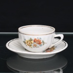 Porcelana Pozzani, Jundiaí - SP (Fundada em 1934 por Francisco Pozzani). Xícara para chá em porcelana nacional,  esmaltação branca, bojo hemisférico moldado com gomos radiais, e alça lateral estilizada. Decoração floral em estampagem policromada composta por ramagens com flores em tonalidades de laranja, amarelo, cinza e azul, entremeadas por folhagens verdes. Filetes dourados delimitam a borda. Pires com motivo floral correspondente e acabamento a ouro. No verso, marca de manufatura em verde com as inscrições Pozzani  Jundiaí. Medidas: Alt.: 4,5 x Comp.: 10 x Larg.: 8cm. ; Pires: Diam.: 13,5cm.