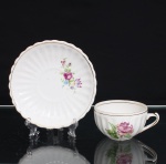 Porcelana Pozzani, Jundiaí - SP (Fundada em 1934 por Francisco Pozzani). Xícara para chá com pires em porcelana  Porcelana Pozzani, Jundiaí  SP. Xícara para chá em porcelana nacional, esmaltação branca, bojo hemisférico moldado com gomos verticais, alça lateral estilizada. Decoração floral em estampagem policromada composta por flor em tonalidades de rosa e vinho, acompanhada de folhagens verdes, realçado com filetes  em douradura junto às bordas. Pires moldado com gomos radiais, aba de contorno ondulado e motivo floral policromo, arrematado por filetação dourada. No verso, marca de manufatura em verde "Pozzani  Jundiaí", acompanhada do número 11. Medidas: Xícara: Alt.: 5 x Comp.: 10,5 x Larg.: 8,5cm. ; Pires: Diam.: 14cm.