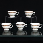 Porcelana Real, Mauá - SP(Fundada em 1943 por Fritz Erwin Schmidt). Conjunto de cinco(05) xícaras para chá em porcelana nacional. c.1950/60. Bojo hemiesférico sobre pé circular elevada, com asa  lateral em voluta. Ornamentação policroma de motivos florais e folhagens distribuídos pelo corpo; junto ao bordo, faixa em tom vinho guarnecida por friso dourado e sequência de festões pendentes, também a ouro. No verso, marca de fábrica sob esmalte, em verde, composta por coroa e inscrições "Reyal  S. Paulo  Made in Brazil". Medidas: Xícara: Alt.: 4,5 x Comp.: 8,5 x Larg.: 7cm.