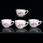 PORCELANA RAMI, Jundiaí  São Paulo (fundada em 1930). Quatro(04) xícaras(sem pires) para chá em porcelana nacional, de esmaltação branca, decoração floral em estampagem policromada, representando orquídeas em tonalidades rosa, verde e amarelo. Bojo hemisférico assente sobre base circular, com alça lateral angular realçada por douradura. Marca de manufatura PORCELANA RAMI na base. Estado conforme fotografias. Medidas: Alt.: 5,5 x Comp.: 10,5 x Larg.: 8,5cm.