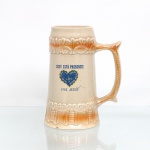 Caneca comemorativa da Legião da Boa Vontade (LBV) em cerâmica esmaltada, formato cônico de estilo germânico, produzida pela Cerâmica Pedreira(Corcovado), Pedreira-SP, c.1950-1970). Corpo creme com ornamentos em relevo ocre, alça moldada e superfície craquelada, face frontal exibe o antigo emblema da LBV(coração azul) com as inscrições "Deus está presente!" e "Viva Jesus!", verso traz a mensagem da "Campanha não deixe morrer uma criança". Na base, apresenta a marca do fabricante gravada em relevo com o modelo 229 e o telefone antigo "Fone - 127".  Medidas: Alt.: x Comp.: x Larg.: cm.