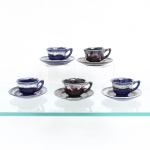 Conjunto de xícaras para café em cerâmica vitrificada, bojo hemisférico e alça lateral em estilizada, esmaltação por imersão e escorrimento, formando faixas irregulares junto aos bordos: três unidades em azul-cobalto, branco e verde-oliva; dois em preto, branco e vinho. Tratamento associado à linguagem da cerâmica de estúdio do pós-guerra, baseada na sobreposição de vidrados e nos efeitos produzidos durante a queima. Sem marca de manufatura. Composto de seis(06) unidades. Medidas: Xícara: Alt.: x Comp.: x Larg.: cm. ; Alt.: x Comp.: x Larg.: cm.
