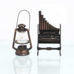 Dois(02) apontadores em miniatura, fabricado na china. Composto por miniatura de lampião a querosene, em metal fundido com globo de vidro, alça móvel e mecanismo de apontador disposto na base, esta marcada "Made in Hong Kong"; e miniatura de órgão de tubos, estruturada com caixa, teclado e sequência escalonada de tubos, incorporando lâmina de apontador no reverso. Acabamento patinado em tonalidades de cobre e castanho, simulando objetos de uso dos séculos XIX e início do XX. Medidas: Alt.: 10,5 x Comp.: 6 x Larg.: 2,5 cm; Medidas: Alt.: 10,5 x Comp.: 5 x Larg.: 4,5 cm.