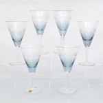 CRISTAL HERING -BLUMENAU. Elegante conjunto de taças para vinho branco em cristal, fabricação nacional, circa 1960-70. Bojo de formato obcônico com transição cromática na tonalidade azul-baikal translúcida na porção inferior, terço superior exibe lapidação em sulcos verticais paralelos, fuste hexagonal sobre base circular. Composto de seis(06) unidades. Um exemplar conserva as etiquetas de manufatura originais. Medidas: Alt.: 15,5 x Diam.: 8 cm.