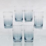 CRISTAL HERING -BLUMENAU. Elegante conjunto de copos em cristal, fabricação nacional, circa 1960-70. Bojo cilíndrico, de base espessa, com transição cromática na tonalidade azul-baikal translúcida na porção inferior, terço superior exibe lapidação em sulcos verticais paralelos, fuste hexagonal sobre base circular. Composto de seis(06) unidades. Medidas: Alt.: 11 x Diam.: 7 cm.