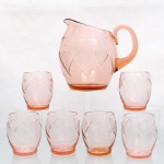 Serviço para água ou refresco em vidro moldado e lapidado, vulgarmente designado "vidro depressão"(depression glass), circa 1930-1940; tonalidade marsala translúcido, composto por uma(01) jarra e seis(06) copos. A jarra apresenta bojo ovoide facetado, bico vertedor proeminente e alça lateral em formato "C" aplicada; copos de corpo abaulado e perfil cilíndrico. Decoração geométrica talhada, constituída por incisões lineares cruzadas em formato de losangos e feixes radiais estilizados mimetizando motivos de leques(fans). Medidas: Jarra: Alt.: x Comp.: x Larg.: cm; Copo: Alt.: x Diam.: cm.