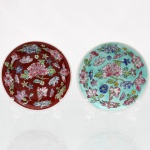 Dois(02) pratos de parede decorativos em porcelana chinesa, estilo Família Rosa (padrão Millefleurs ou Wan Shou Wu Jiang modificado), circa meados do século XX. O primeiro exemplar exibe esmaltação em fundo marrom-avermelhado (sangue-de-boi), enquanto o segundo apresenta cobertura na tonalidade verde-turquesa. Ambas são densamente decoradas por peônias centrais envoltas por composição livre de crisântemos, magnólias, flores de lótus e ramificações fitomórficas em relevo esmaltado (fencai). O reverso apresenta base anelar, fixação artesanal de passador metálico(adaptado) triangular por massa adesiva(durepox) cinza para suspensão em parede e vestígios de marca de manufatura carimbada em tom vermelho, contendo numeração parcial sob as linhas de marcação. Medidas: Diam.: 10cm.