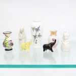 Conjunto composto por seis(06) peças de pequenas dimensões, reunindo dois vasos, duas figuras de elefantes e dois personagens. Inclui vaso de bojo globular com ornamentação floral policroma; vaso alongado em porcelana branca decorado com hastes de bambu e caracteres orientais; pequeno vaso com faixa em tom pêssego, douração e motivo floral; elefantes modelados em amarelo e preto, este último com detalhes dourados; além de duas figuras em porcelana branca, uma representando personagem masculino de vestes talares e outra figura feminina ou infantil com cobertura de cabeça perfurada para uso utilitário. Uma das peças conserva marca "Made in China" em vermelho. Medidas peça maior: Alt.: 10 x Diam.: 5 cm. Medidas peça menor: Alt.: 4 x Comp.: 5 x Larg.: 2 cm.