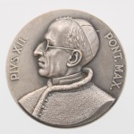 Medalha comemorativa em metal prateado, cunhada para o XXXVI Congresso Eucarístico Internacional, realizado no Rio de Janeiro em 1955. Anverso com busto em perfil do papa Pio XII, voltado à esquerda, acompanhado da legenda latina "PIVS XII  PONT. MAX.". Reverso com emblema do congresso, constituído por monograma cruciforme sobreposto por esfera armilar e elementos cruzados, circundado pela inscrição "XXXVI CONGRESSO EUCARISTICO INTERNACIONAL / RIO DE JANEIRO /1955". Na base da composição figura a assinatura "MONTINI". O congresso realizou-se no Rio de Janeiro em julho de 1955, durante o pontificado de Pio XII. Medida: Diam.: 50mm.