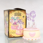 Peça decorativa musical e luminosa "Crystal Flash - Guoqin Octave", século XX. Composição confeccionado em material plástico moldado nas tonalidades creme, rosa e lilás, formada por base circular com aplicação frontal em forma de coração e inscrição "LOVE", encimada por grupo de três cisnes translúcidos junto a árvore florida. Dotada de mecanismo musical e sistema de iluminação, com chave de acionamento na base. Acompanha embalagem original "Crystal Flash - Guoqin Octave". Medidas: Alt.: 19,5 x Diam.: 13cm.