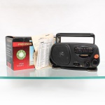 Rádio portátil multifaixas da marca Precision. Receptor de rádio em gabinete preto de material sintético, com alça superior para transporte, alto-falante frontal, mostrador analógico e comandos de sintonia, volume e seleção de faixa. Recepção FM, MW e SW, com indicação AC/DC no painel. Acompanha embalagem original e documentação de uso. Medidas: Alt.: 17 x Comp.: 23,5 x Larg.: 8,5cm.