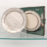 Bandeja circular em aço inoxidável 18/8, marca Tramontina, linha Crystal. Formato circular, com centro liso, ligeiramente rebaixado, aba elevada e bordo ornamentado por friso torcido. Etiqueta de procedência com inscrições "Aço Inox 18/8 - Tramontina -Stainless Steel". Conserva caixa original da Linha Crystal. Medida: Diam.: 30cm.