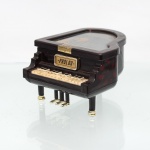 Caixa de música em formato de piano de cauda, marca Prolog; confeccionado em material sintético de tonalidade castanho-escura, com efeito marmorizado avermelhado, teclado miniaturizado em tons de marfim e preto, pés com terminais dourados e conjunto de pedais. Tampa articulada com composição gráfica de temática musical e inscrição "Pianissimo - Più mosso". Interior com mecanismo musical disposto sob painel transparente decorado por pautas e notas. Placa frontal com inscrição PROLOG. Medidas: