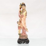 Escultura religiosa oriental executada em estuque moldado e policromado, representando a divindade Guanyin(Kuan Yin) em sua manifestação iconográfica como protetora das crianças (Songzi Guanyin). A figura feminina veste túnica fluida com drapeados sinuosos, ostentando penteado alteado com adorno capilar e portando ramo floral na mão destra, ladeada por figura infantil em atitude de veneração junto à base. O conjunto assenta sobre plinto semiesférico texturizado mimetizando escamas ou rochas, fixado a uma base em madeira escura entalhada e vazada com motivos de volutas estilizadas. Apresenta avarias, vide fotos. Medidas: Alt.: 43,5 x Comp.: 14 x Larg.: 14cm