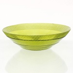 Fruteira rasa executada em vidro moldado, de tonalidade "chartreuse" translúcida, estilo Mid-Century Modern, circa 1960-1970. Apresenta formato hemisférico raso, aba ligeiramente inclinada, ornamentada por faixas concêntricas alternadas, debrum perimetral e anel intermediário exibem padronagem em relevo de pequenas esferas justapostas, emulando a técnica de vidro bolha ou hobnail. Centro e faixas divisórias mantêm acabamento liso, assentando sobre base anelar plana com marcas naturais de fricção no reverso. Medidas: Alt.: 8,5 x Diam.: 28 cm.