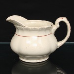 W.H. GRINDLEY, Staffordshire - Inglaterra(Fundada por William Harry Grindley em 1880). Cremeira  em faiança inglesa da década de 1940/50, padrão "Creampetal"; esmaltagem de tom marfim, decorado com frisos em douradura e tom coral, corpo bojudo de seção polilobada moldada em relevo, assente sobre base circular; bico vertedor revirado para fora, asa lateral em voluta, borda relevada com perolados e ondulações. Marca da manufatura no verso. Medidas: Alt.:  x Comp.  x Larg.:  cm.
