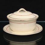W.H. GRINDLEY, Staffordshire - Inglaterra(Fundada por William Harry Grindley em 1880). Açucareiro em faiança inglesa da década de 1940/50, padrão "Creampetal"; esmaltagem de tom marfim, decorado com frisos em douradura e tom coral, bojo hemisférico fixado sobre preentoir circular, tampa ligeiramente abaulada encimada por puxador em arco. Marca da manufatura no verso. Medidas: Alt.:  x Diam. cm.