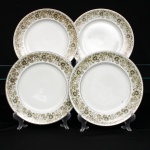 Conjunto composto por quatro(04) pratos rasos em porcelana nacional, c. 1960/70. Esmaltagem vítrea na cor branca, borda contornada por filete em prata, orla recebe ornamentação perimetral contínua transferida sob o vidrado, composta por ramagens fitomórficas, folhas lanceoladas e corolas florais estilizadas em nuances de verde-oliva, ocre e castanho, com contornos lineares pretos e realces em esmalte branco. Marca da manufatura no verso. Medida: Diam.: 25,5 cm.