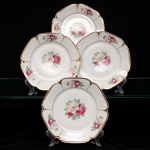 Porcellana Mauá, Mauá - SP(Fundada em 1937 por Fritz Erwin Schmidt / ativa até 1968). Conjunto de pratos rasos em porcelana nacional, c.1940-50. Formato octogonal com bordas arredondadas e debrum recortado, delimitado por filete dourado aplicado na orla. Centro decorado por motivo pictórico decalcado composto por um buquê de rosas em tons de rubi, rosa-chá e branco, guarnecido por folhagens em verde-oliva e esmeralda, que se replicam  dispostos de forma simétrica nas quatro extremidades da aba. O reverso apresenta carimbo de manufatura, contendo a inscrição em arco "Porcellana Mauá" circundando o logotipo estilizado da empresa e a representação gráfica de uma locomotiva a vapor, em referência histórica à estrada de ferro regional. Composto de quatro(04) unidades. Medida: Diam.: 24 cm.