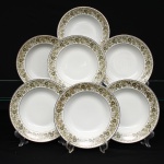 Porcelana Real, Mauá - SP(Fundada em 1943 por Fritz Erwin Schmidt). Conjunto composto por sete(07) pratos fundos em porcelana nacional, c.1960/70. Esmaltagem vítrea na cor branca, borda contornada por filete em prata, orla recebe ornamentação perimetral contínua transferida sob o vidrado, composta por ramagens fitomórficas, folhas lanceoladas e corolas florais estilizadas em nuances de verde-oliva, ocre e castanho, com contornos lineares pretos e realces em esmalte branco. Marca da manufatura no verso. Medida: Diam.: 23 cm.