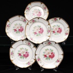 Porcellana Mauá, Mauá - SP(Fundada em 1937 por Fritz Erwin Schmidt / ativa até 1968). Conjunto de pratos para sobremesa em porcelana nacional, c.1940-50. Formato octogonal com bordas arredondadas e debrum recortado, delimitado por filete dourado aplicado na orla. Centro decorado por motivo pictórico decalcado composto por um buquê de rosas em tons de rubi, rosa-chá e branco, guarnecido por folhagens em verde-oliva e esmeralda, que se replicam  dispostos de forma simétrica nas quatro extremidades da aba. O reverso apresenta carimbo de manufatura, contendo a inscrição em arco "Porcellana Mauá" circundando o logotipo estilizado da empresa e a representação gráfica de uma locomotiva a vapor, em referência histórica à estrada de ferro regional. Composto de seis(06) unidades. Medida: Diam.: 18,5 cm.