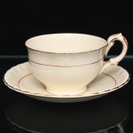 W.H. GRINDLEY, Staffordshire - Inglaterra(Fundada por William Harry Grindley em 1880). Xícara para chá em faiança inglesa da década de 1940/50, padrão "Creampetal"; esmaltagem de tom marfim, decorado com frisos em douradura e tom coral, bojo hemisférico sobre base circular, asa lateral em voluta, borda do pires relevada com perolados e ondulações. Marca da manufatura no verso. Medidas: Xícara: Alt.: 5,5 x Comp. 12 x Larg.: 9,5 cm; Pires: Diam.: 14,5 cm.